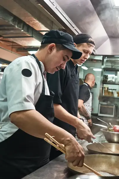 Twee koks bakken gerechten in restaurantkeuken