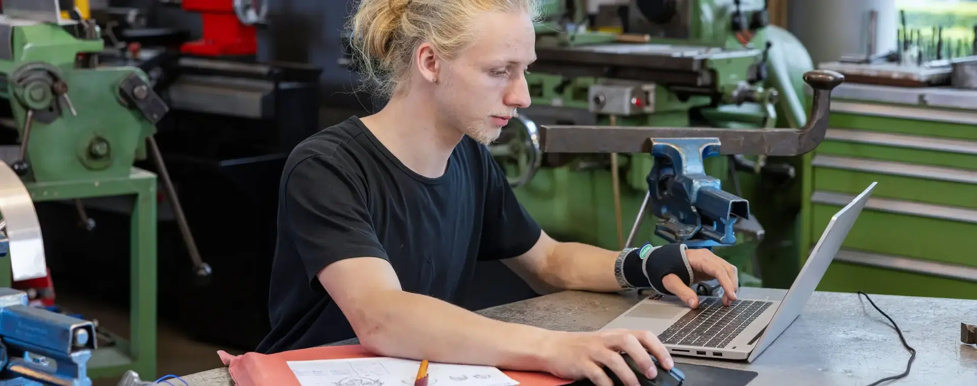 Student achter computer omringd door technische apparatuur