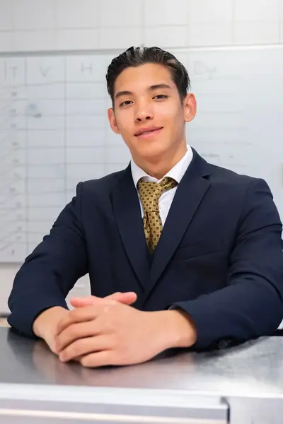 Hospitality student staat in een keukenomgeving en kijkt zelfverzekerd in de camera.