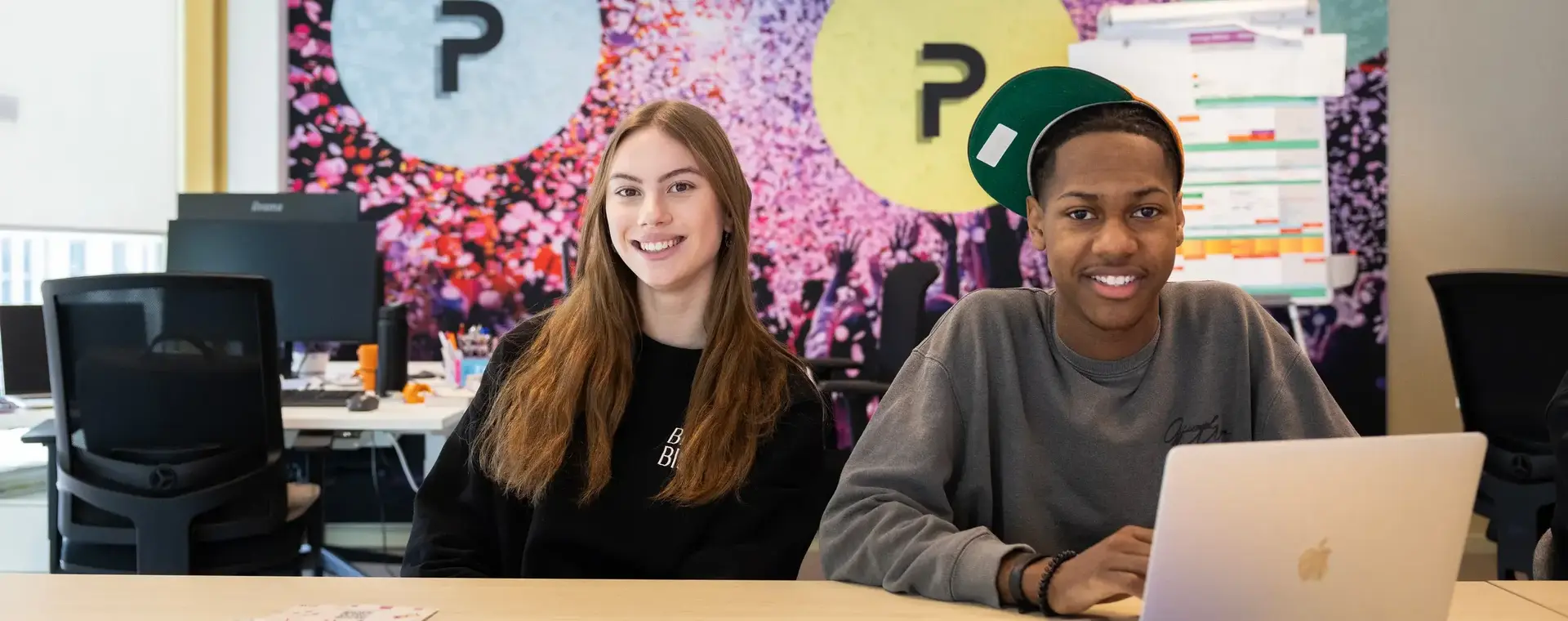 Twee studenten achter bureau met laptop