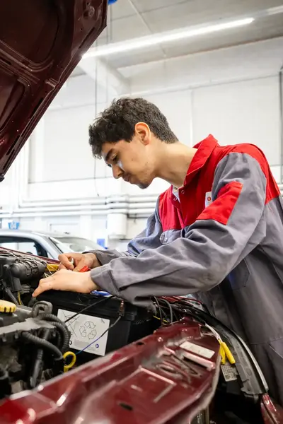 Student in ROCvA-overall checkt auto onder de motorkap.