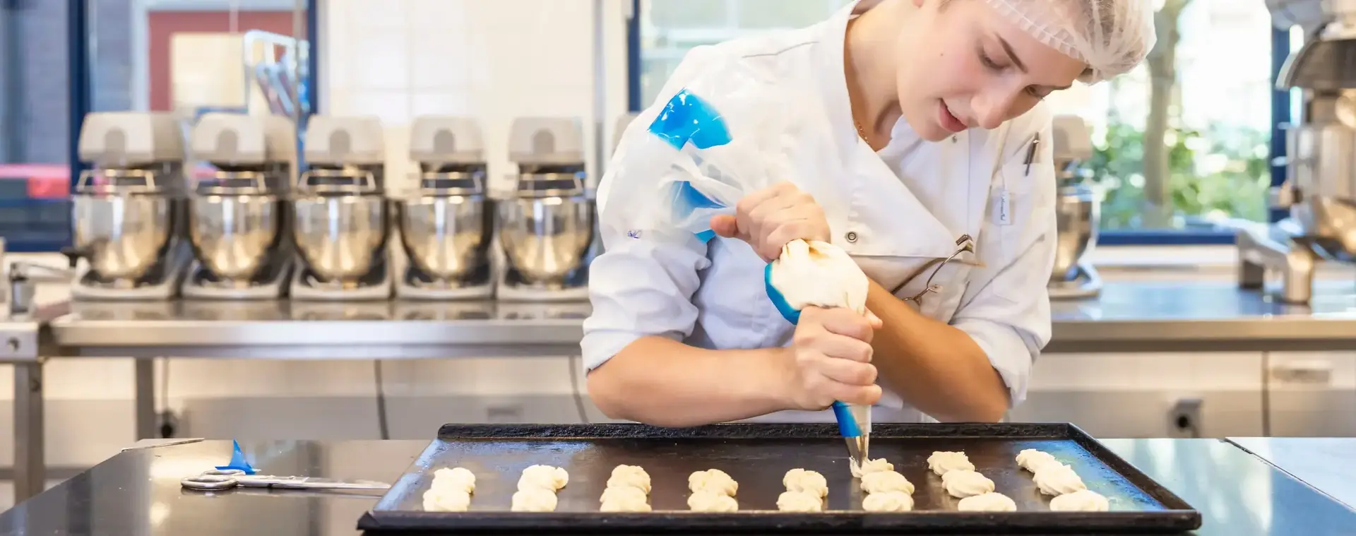 Patissier werkt geconcentreerd aan een bakopdracht in een patisserie keuken