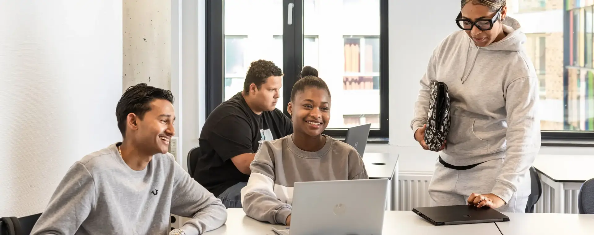 Vier studenten zitten aan bureau achter laptop