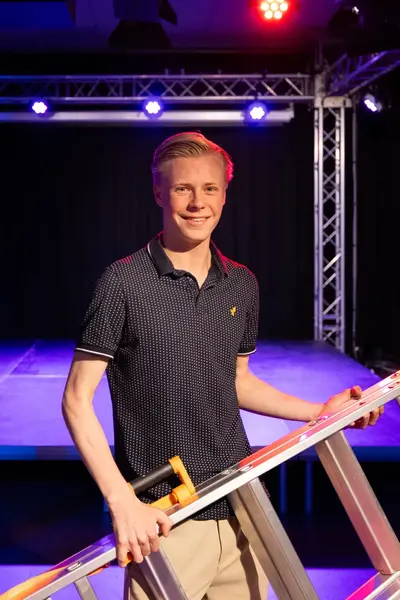 Student voor een podium draagt een trap.