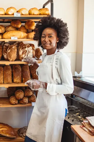 Bakker in bakkerszaak omringd door uiteenlopende broden