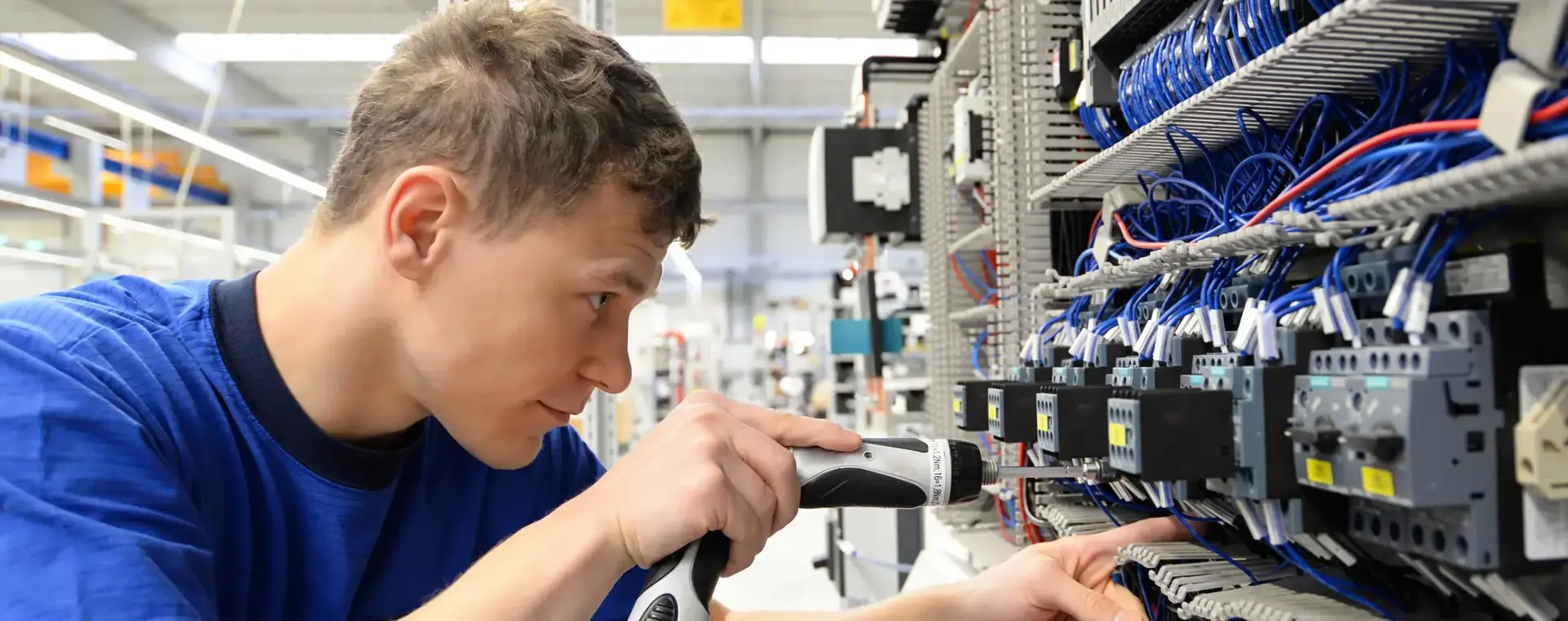 Jonge man werkt met kleine schroefmachine aan elektriciteitsinstallatie (middenspanning)