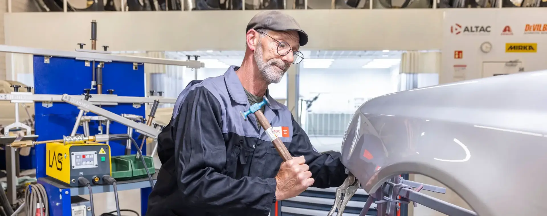 Automonteur met hamer herstelt schade aan carrosserie