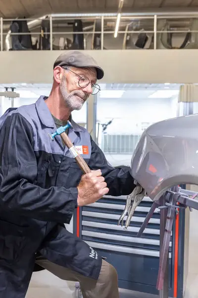 Automonteur met hamer herstelt schade aan carrosserie