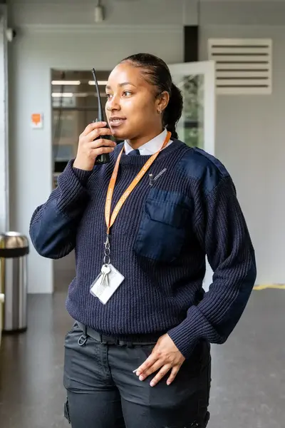 Vrouwelijke beveiliger spreekt in walkietalkie op gang