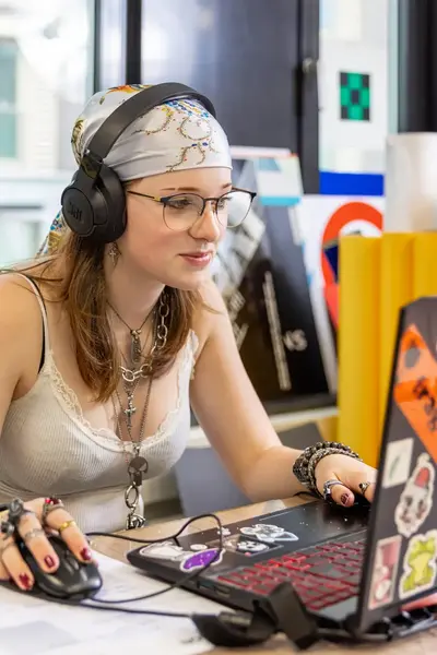 Studente met koptelefoon op werkt op haar laptop.