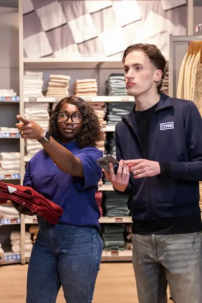 Twee medewerkers in een winkel overleggen tussen schappen met handdoeken.