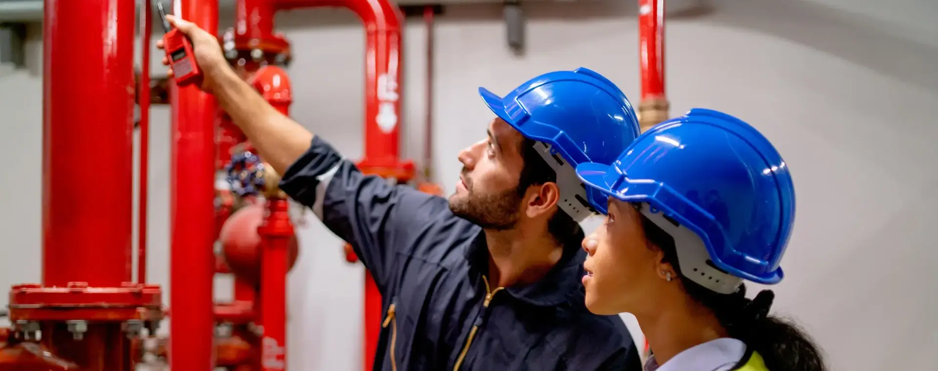 Uitvoerder bouw bekijkt met een collega buizen in een gebouw