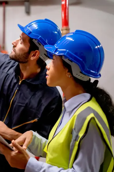 Uitvoerder bouw bekijkt met een collega buizen in een gebouw