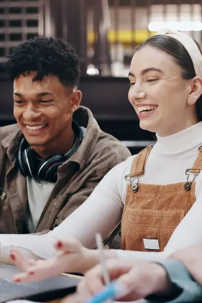 Vier lachende studenten zitten samen achter een laptop aan een opdracht te werken.