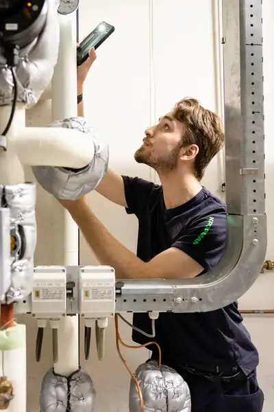 Monteur inspecteert isolatiebuizen en meet installatie.