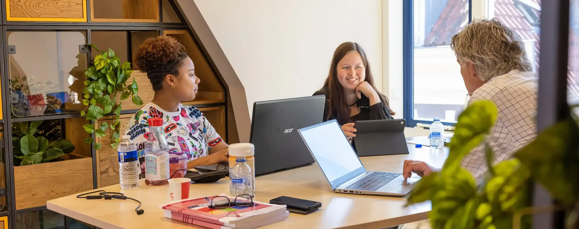 Groepje van drie aan tafel achter laptops