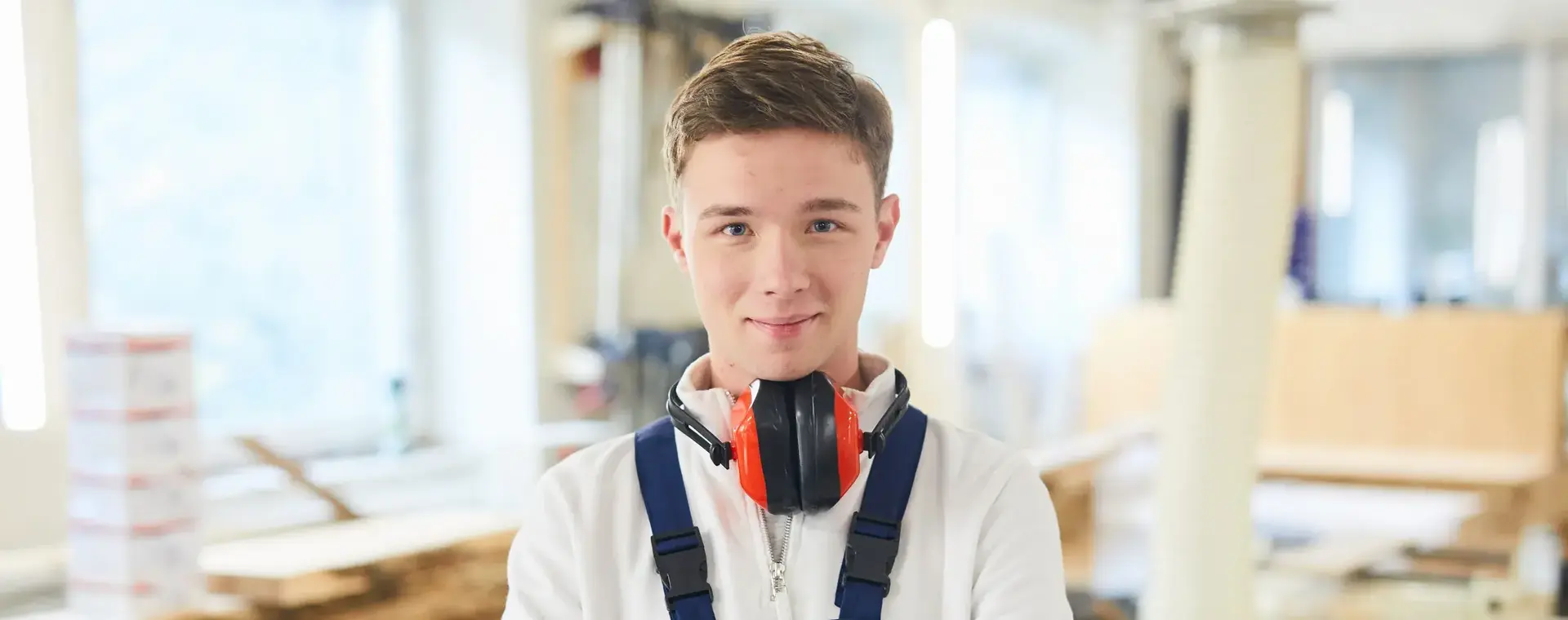 Jongen met gehoorbescherming in timmer werkplaats.