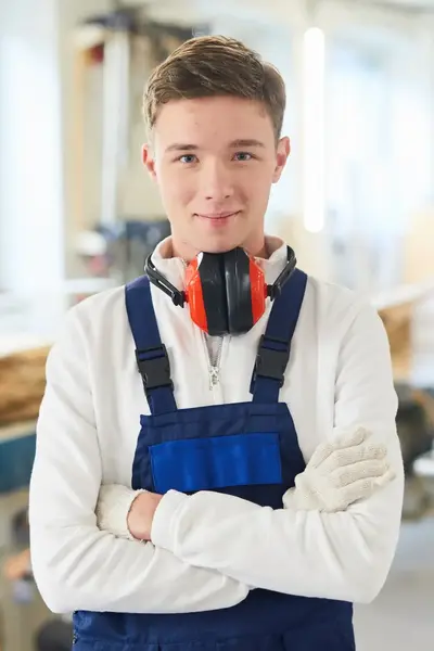 Jongen met gehoorbescherming in timmer werkplaats.