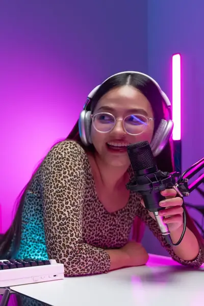 Een man en vrouw zitten in een radio studio achter twee microfoons met elkaar te praten en radio te maken.