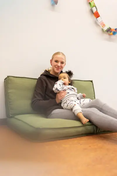 Studente met peuter op schoot op bank
