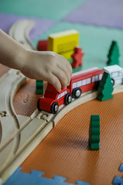 Kinderhand speelt met rode houten speelgoedtrein 