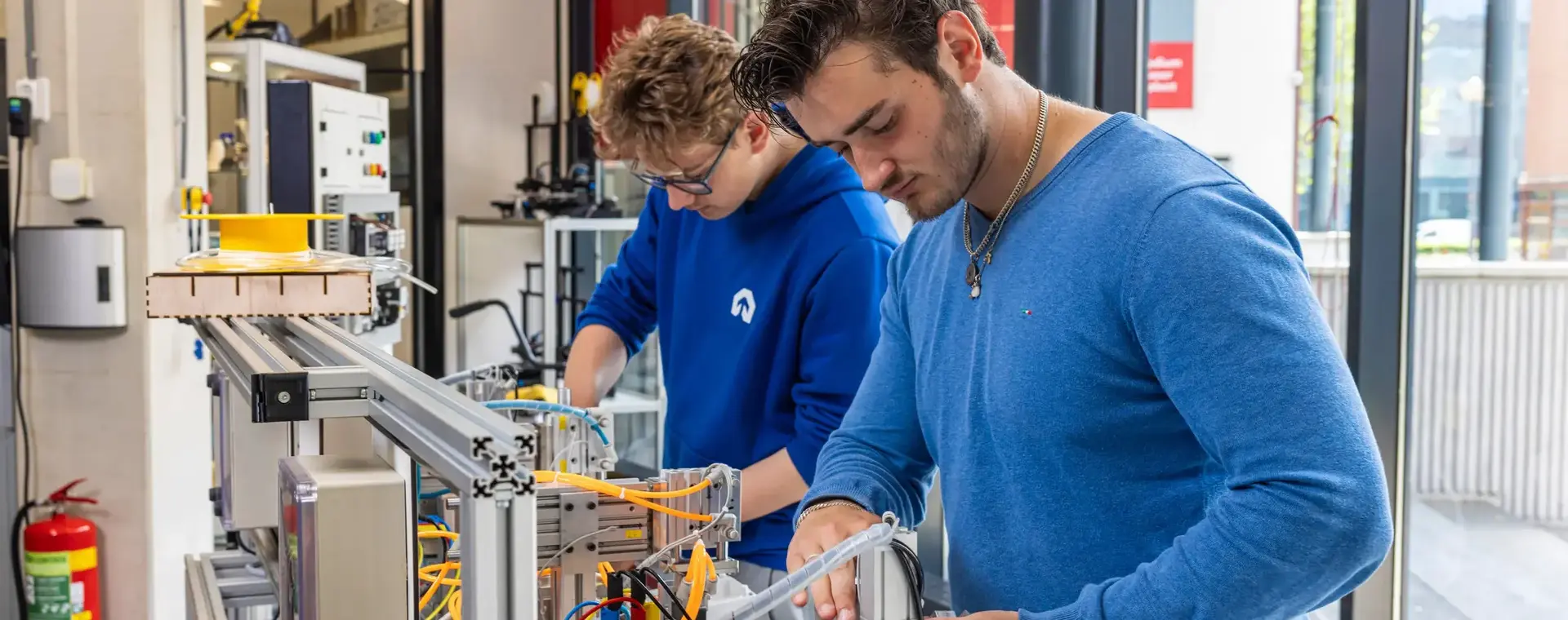 Studenten werken aan een technische installatie tijdens de praktijkles.
