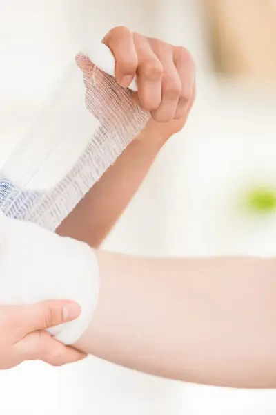 Verpleegster doet verband om pols en hand van een patiënt