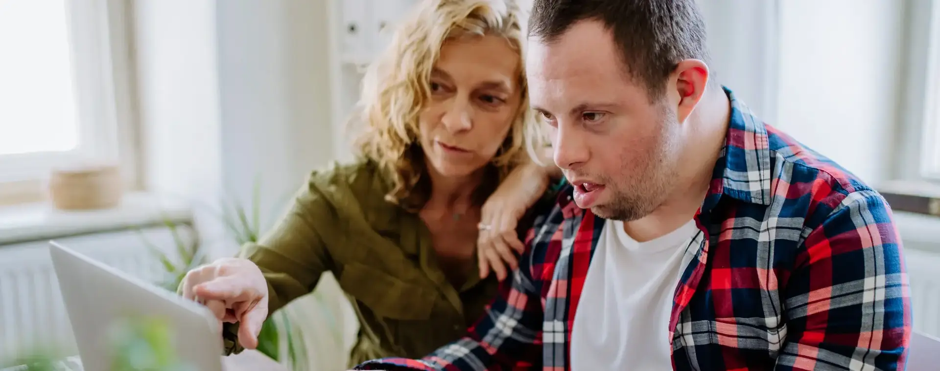 Vrouw helpt man met syndroom van Down met computer