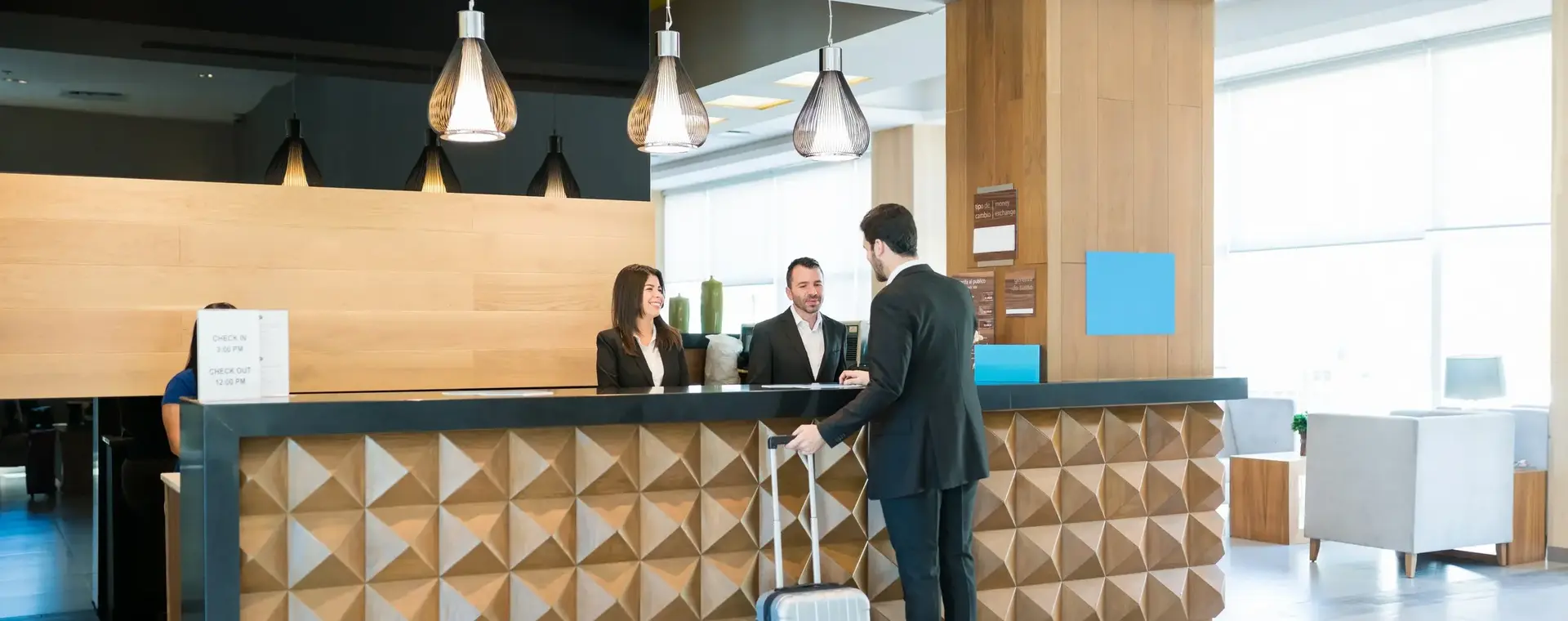 Hotelgast wordt professioneel ontvangen aan de receptiebalie door medewerkers
