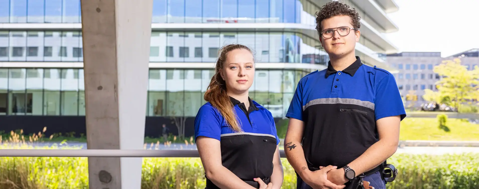 Twee studenten handhaving poseren in uniform voor een schoolgebouw.