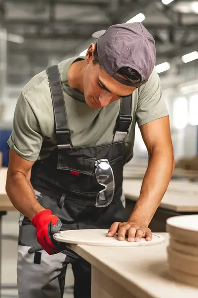 Student in werkkleding bewerkt hout op werkbank