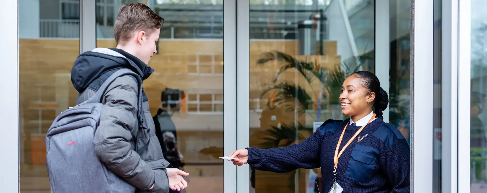 Beveiliger reikt een pasje uit aan bezoeker