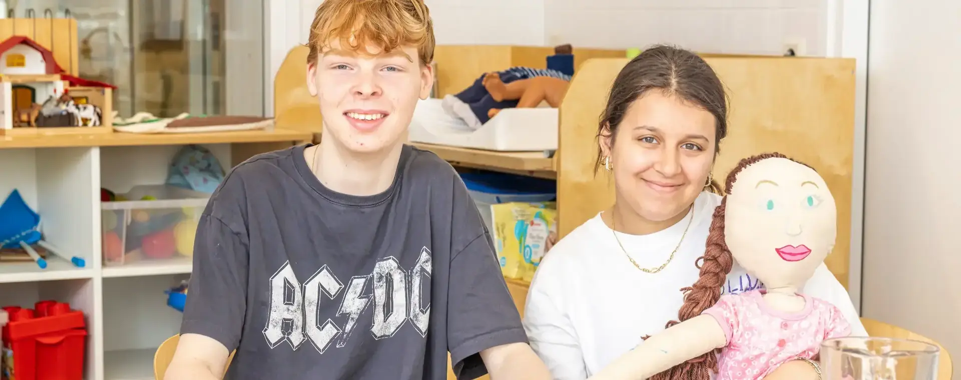 Jonge student en meisje aan een kindertafel met drinken en pop