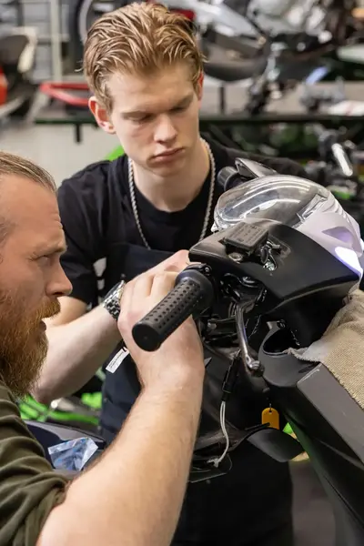 Docent en student werken aan een scooter in garage