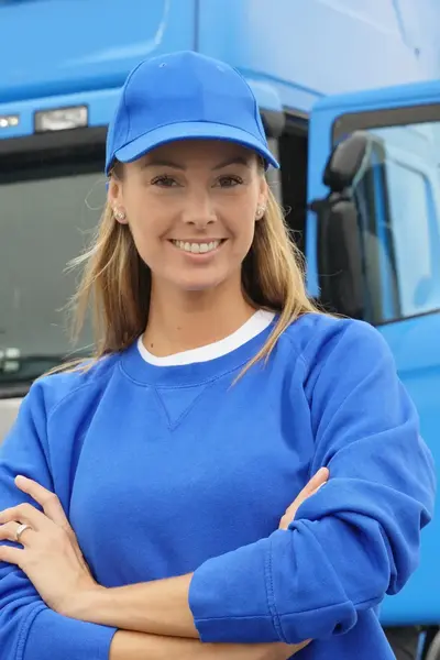 Vrachtwagenchauffeur in blauw poseert voor blauwe vrachtwagen