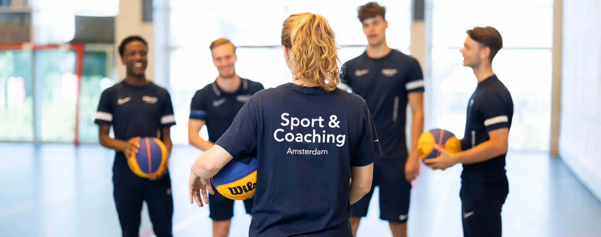 Studenten in sportzaal met ballen in de hand