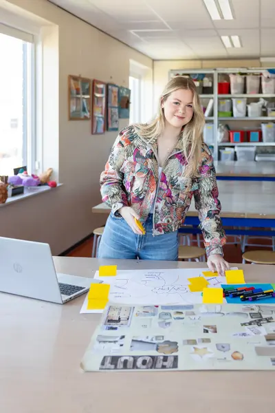 Student werkt aan een opdracht met post-its en schetsen op tafel.