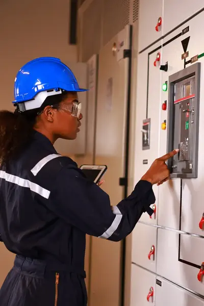 Elektromonteur met bouwhelm en veiligheidsbril controleert elektrotechnische installatie