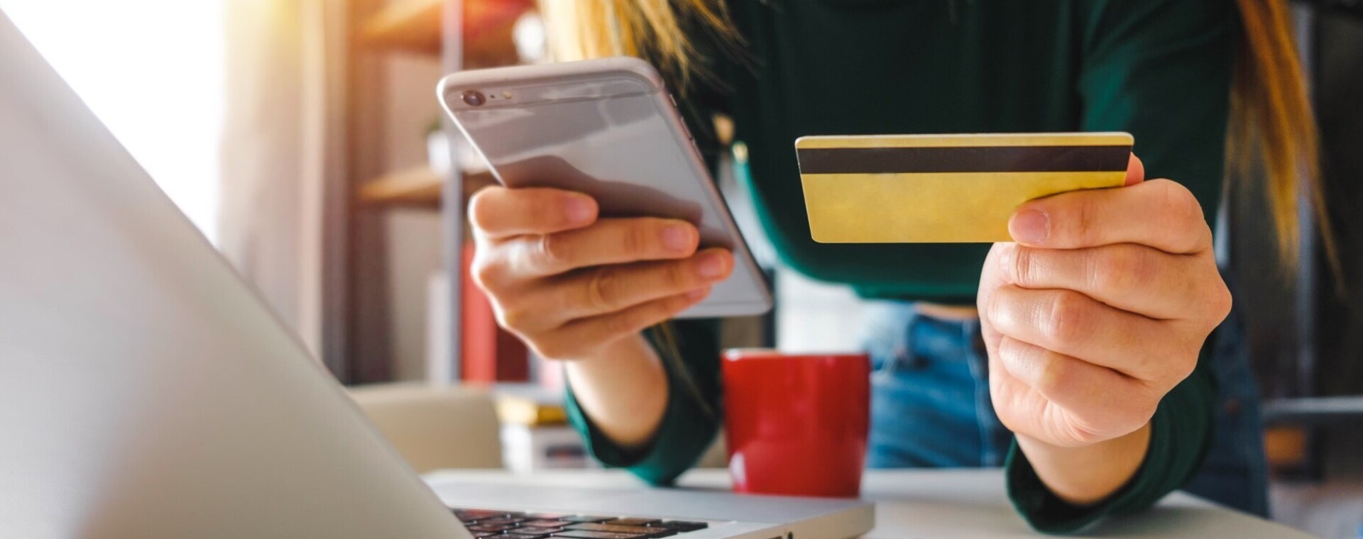 Handen met mobiele telefoon en bankkaart en een laptop