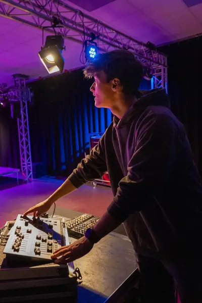 Student met regelt met lichtpaneel het licht op het podium.