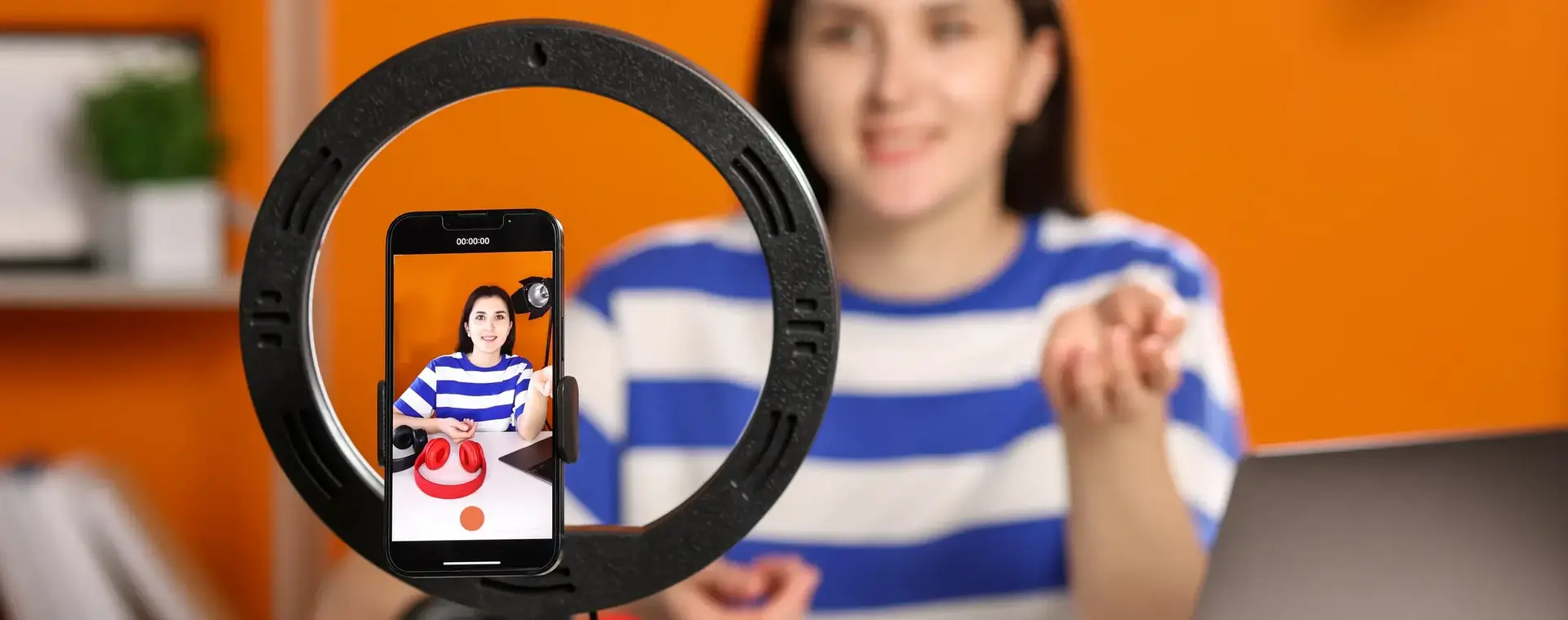Meisje met mobiele telefoon en ringlight die een social media filmpje van zichzelf aan het maken is.