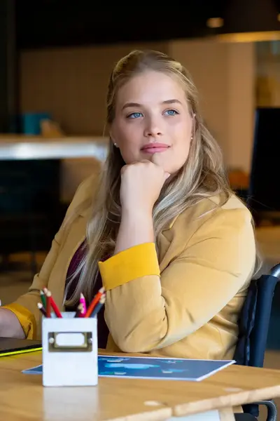 Student achter laptop met koffie en pennenbak