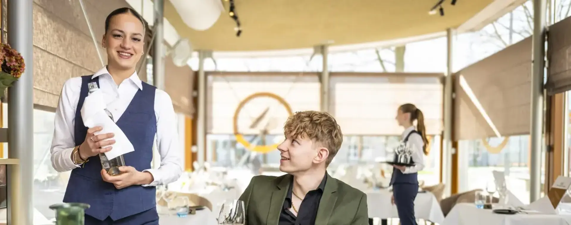Een leerling bedient een gast in het restaurant