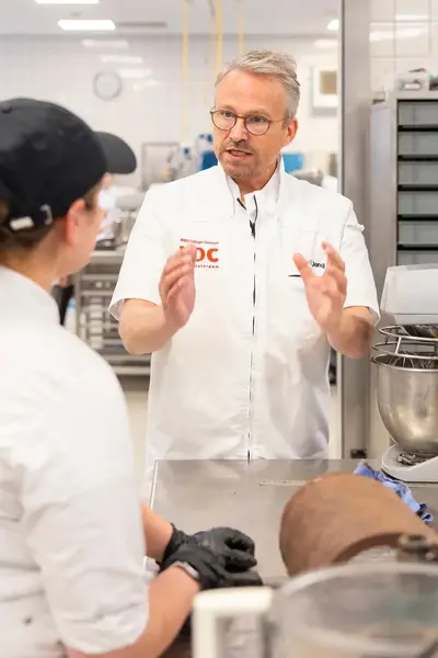 Docent geeft les aan koksleerling in keuken