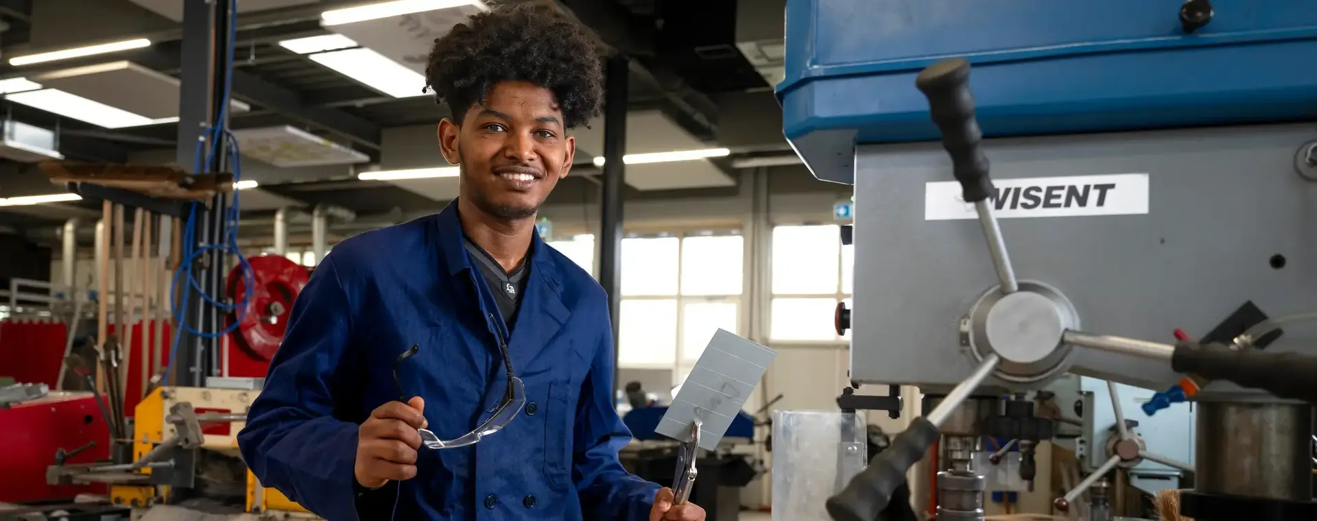 Student in blauw werkpak in een fabrieksomgeving