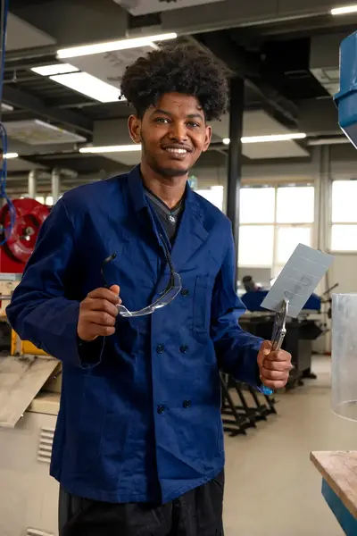 Student in blauw werkpak in een fabrieksomgeving