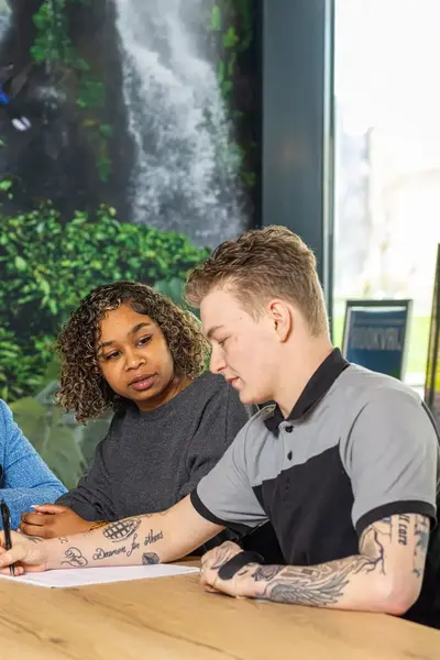Drie studenten Veiligheidscollege aan tafel met laptop.