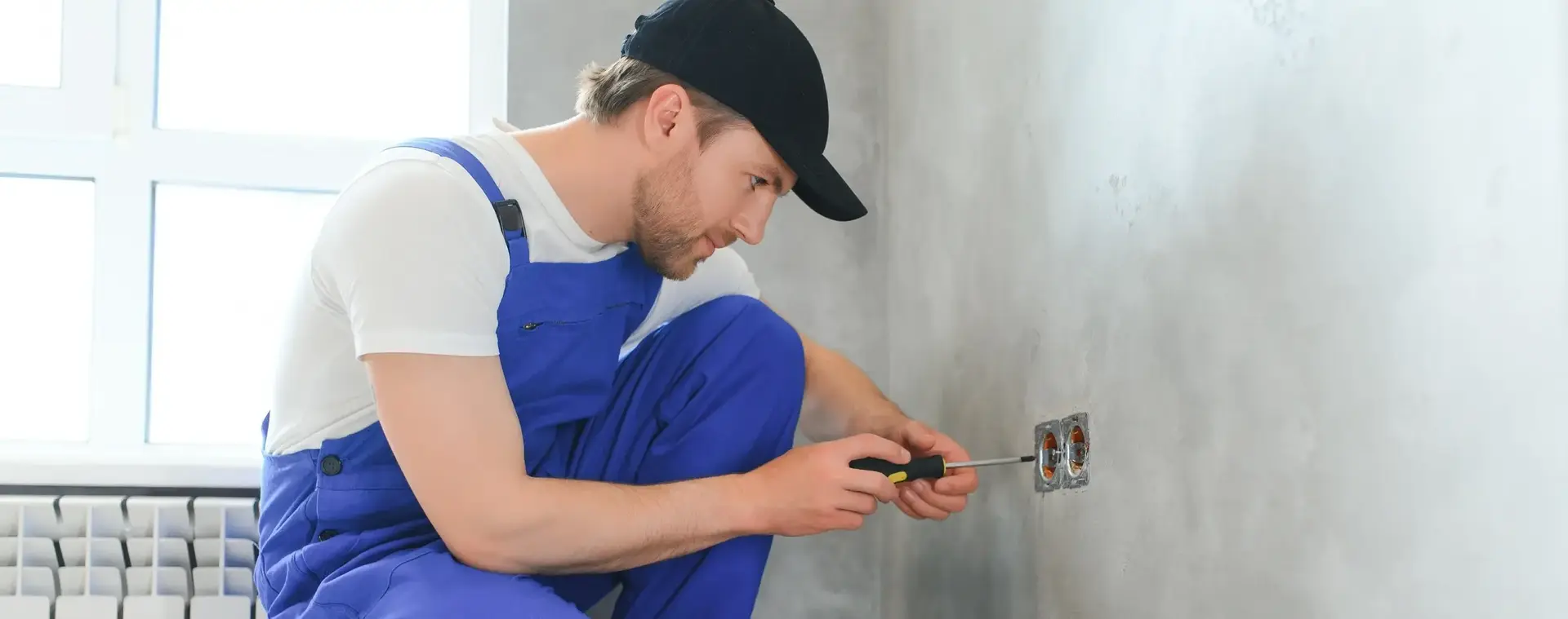 Jonge man werkt aan een stopcontact in een woning