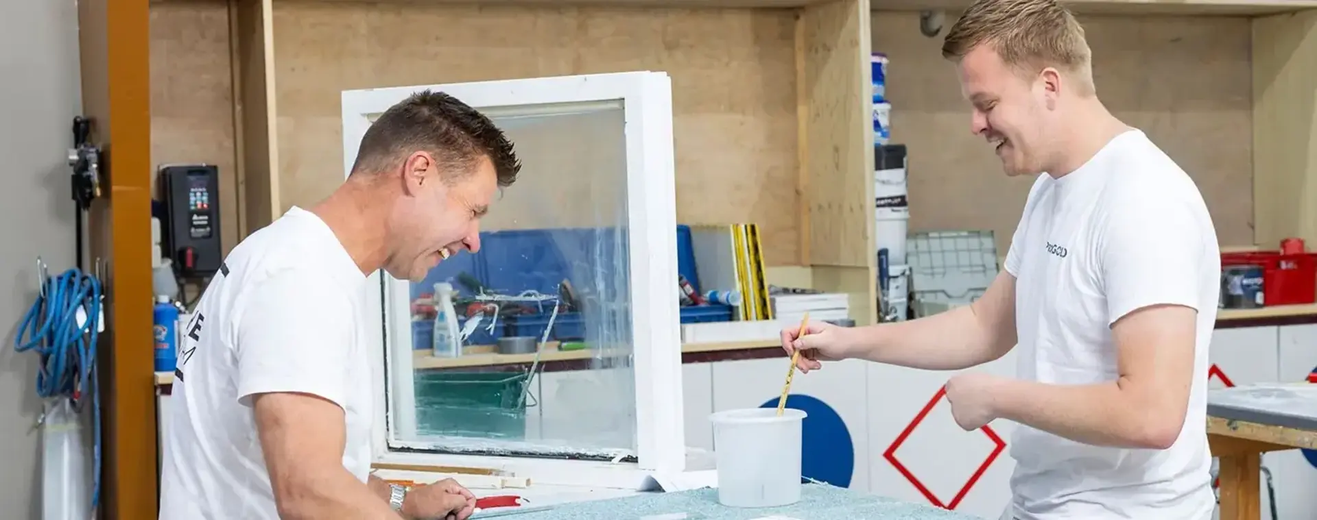 Twee schilder in werkplaats schilderen een kozijn