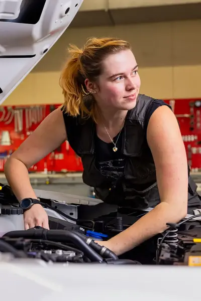 Studente sleutelt aan de motor van auto in garage